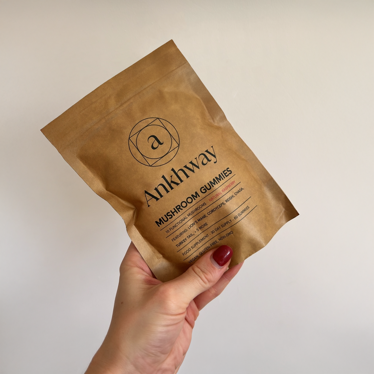Hand holding a brown package of Ankhway mushroom gummies