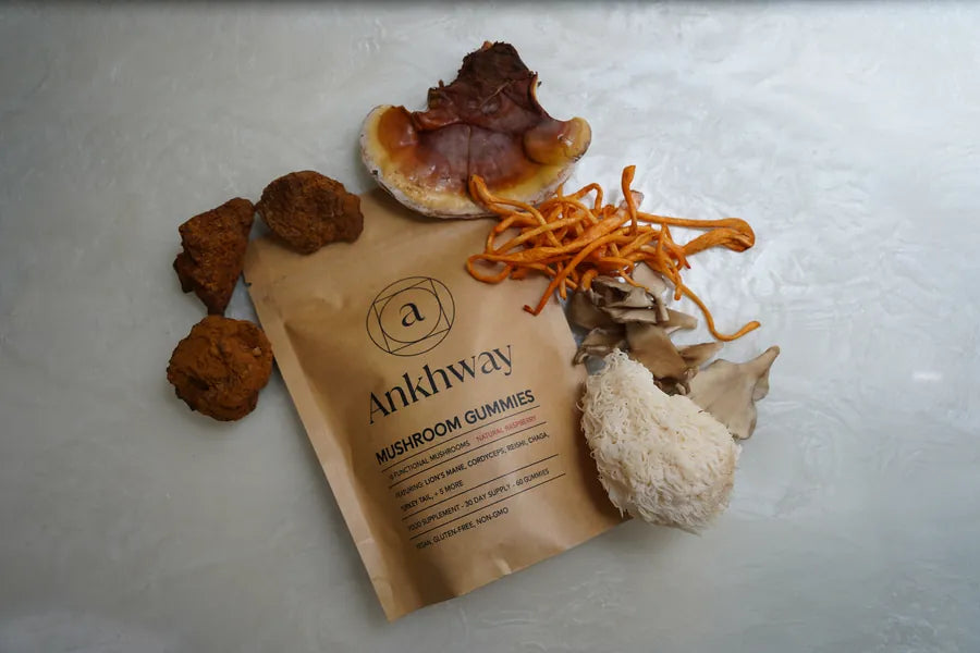 Packet of Ankhway mushroom gummies surrounded by various mushrooms on a light surface.
